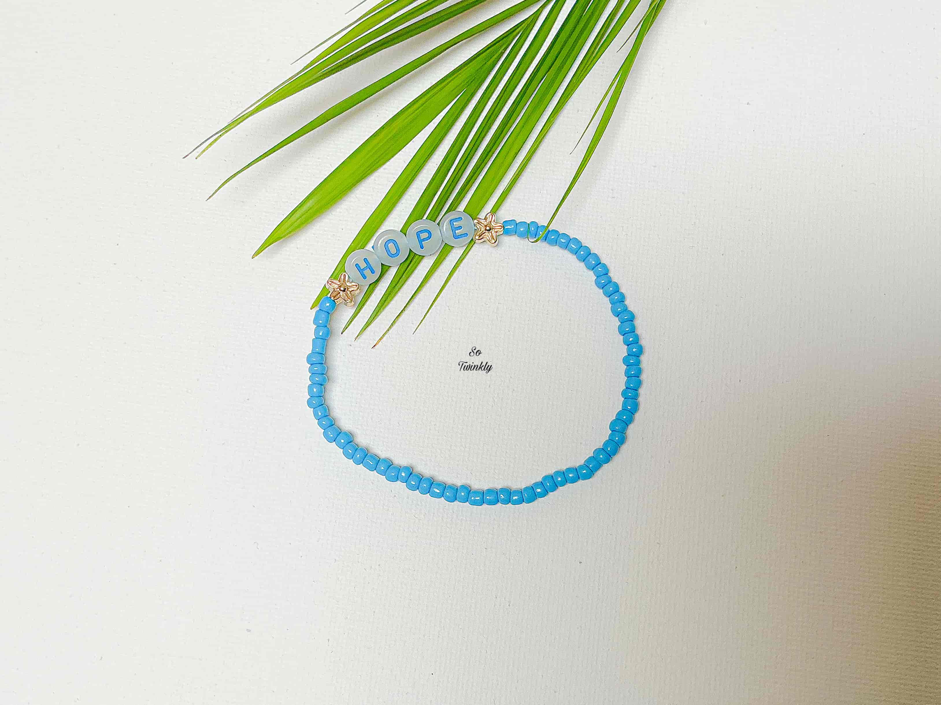 Handmade bracelet with soft blue acrylic beads and a central message charm that says “Hope”