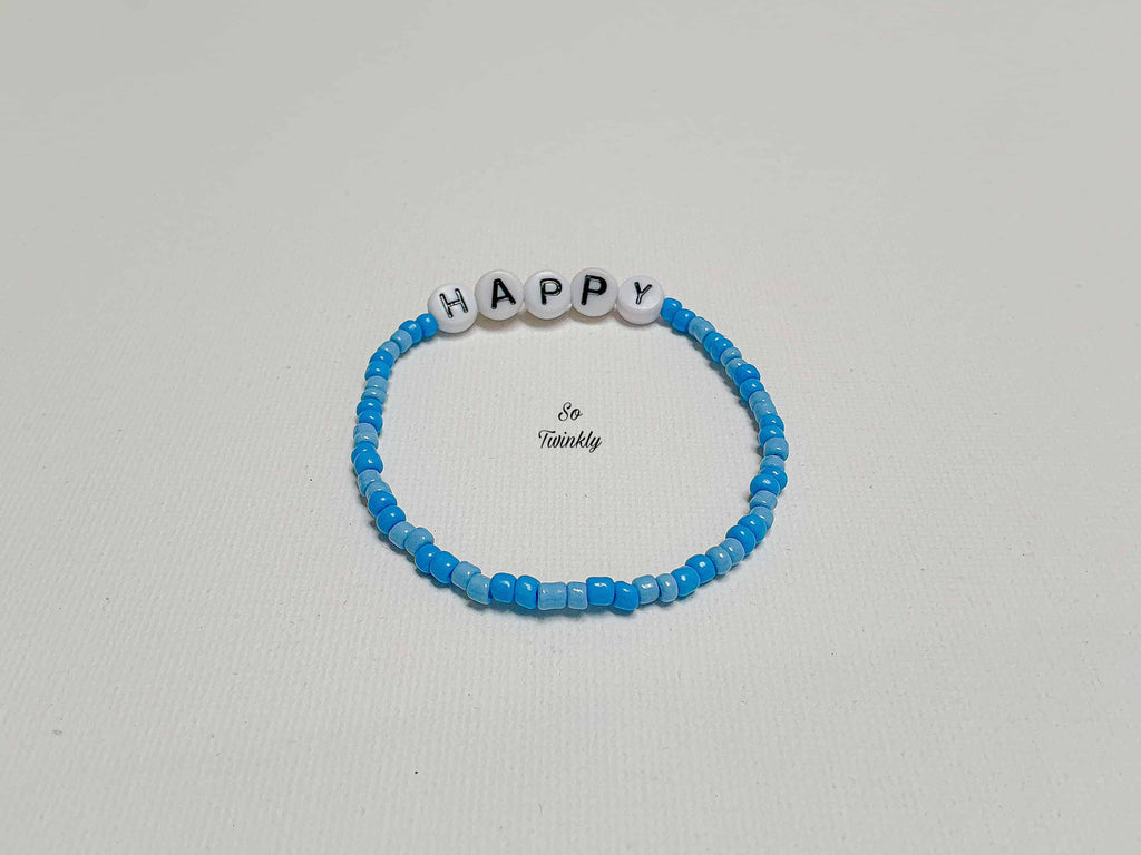 Flat lay of handmade Happy bracelet with soft and deep blue acrylic beads arranged in a subtle gradie