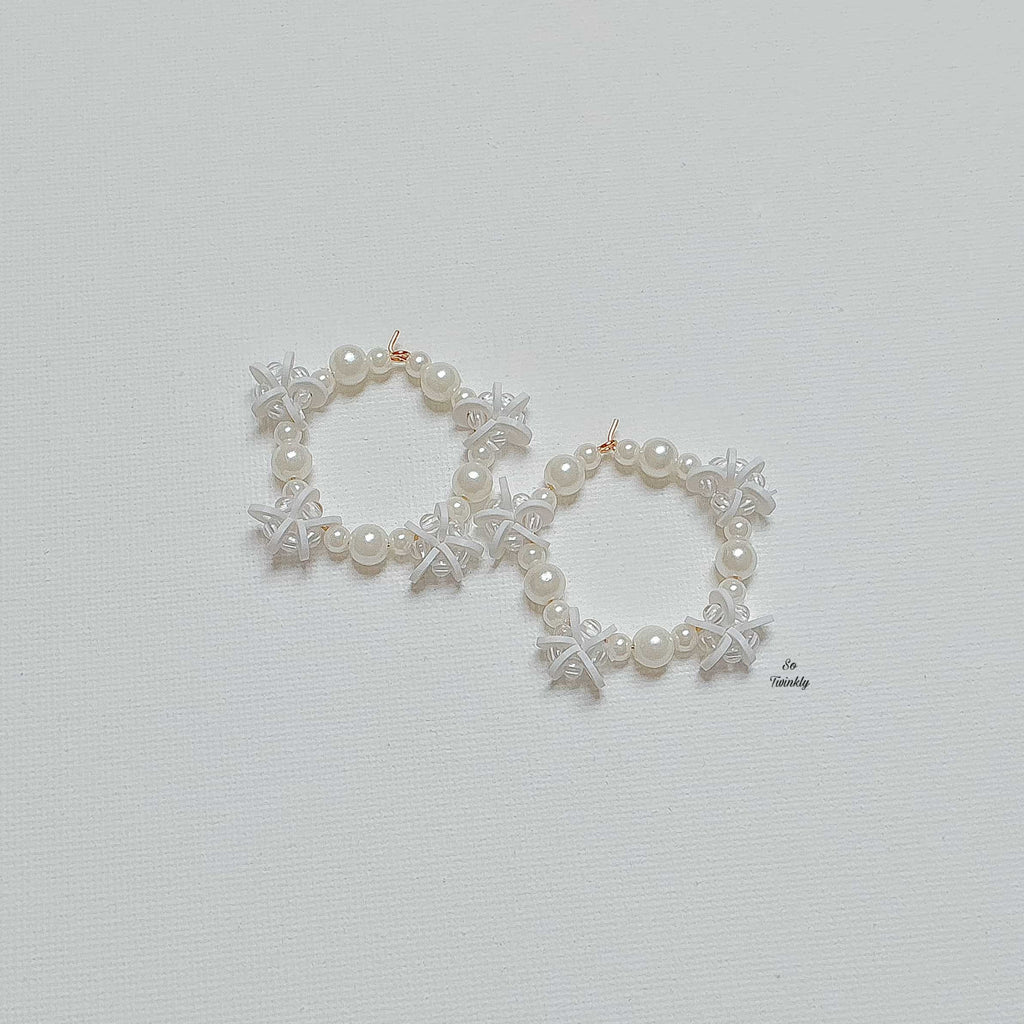 Flat lay of pearl and star earrings featuring white beads and delicate star charms on alloy ho