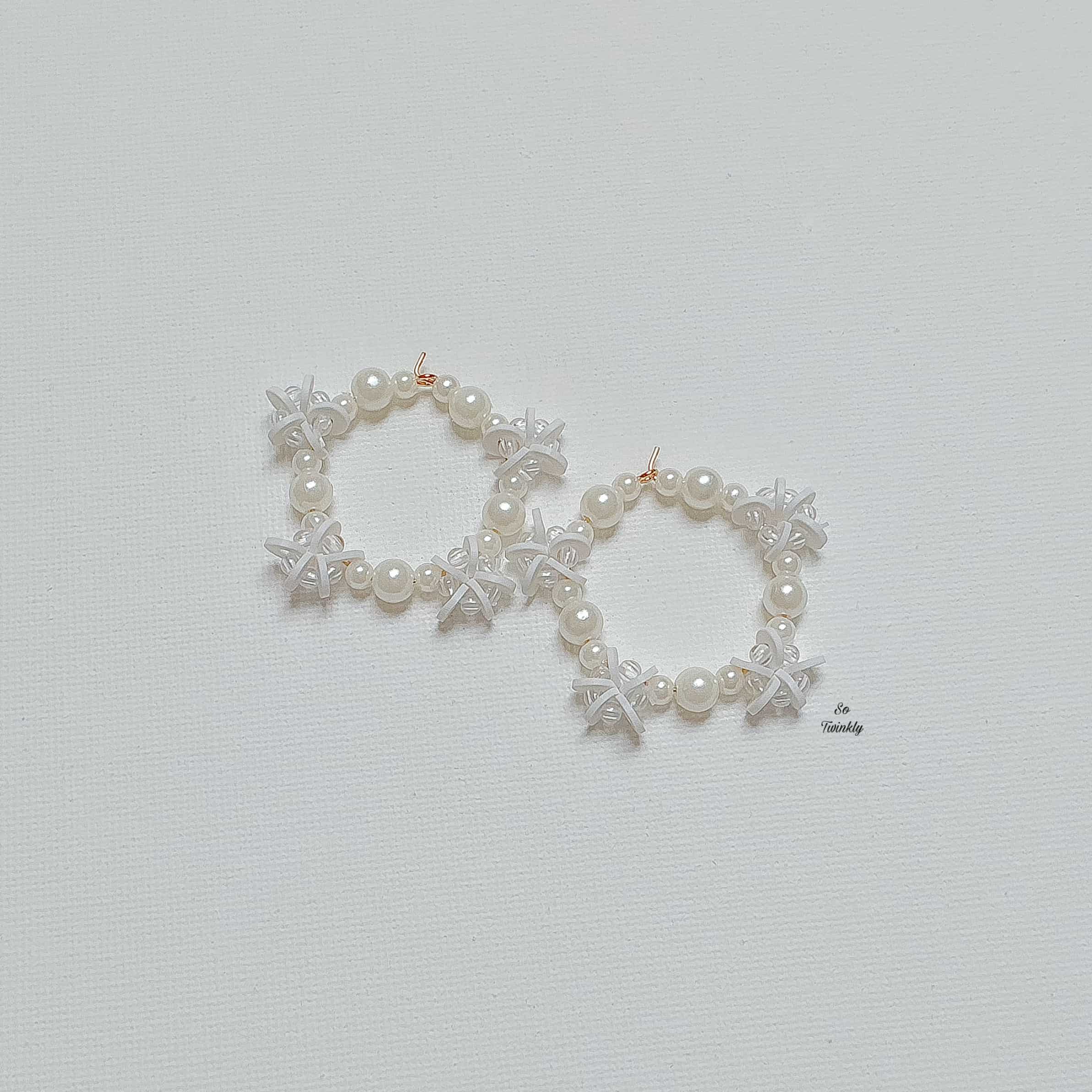 Flat lay of pearl and star earrings featuring white beads and delicate star charms on alloy ho