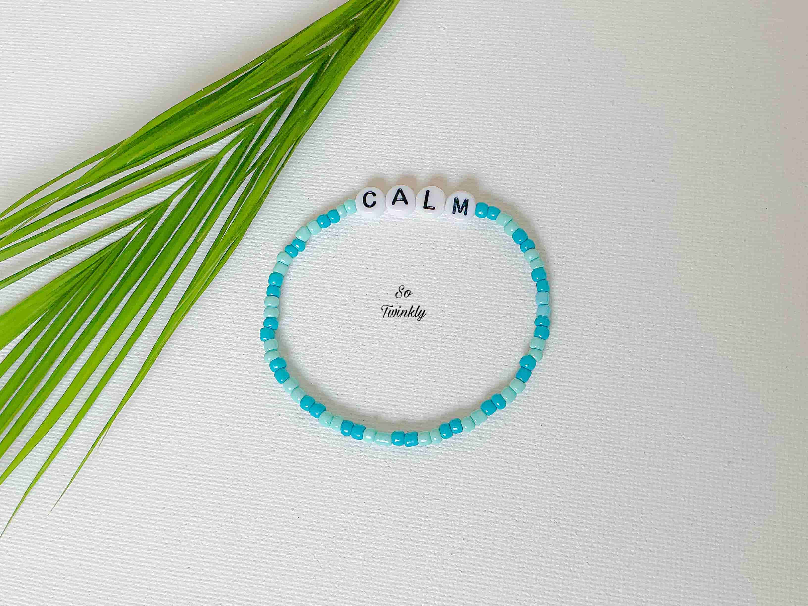 Handmade bracelet with soft blue acrylic beads and a central message bead that says “Calm”