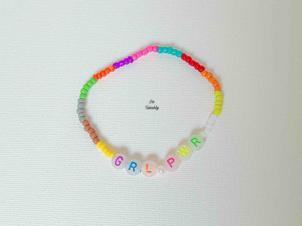 Flat lay of colorful GIRL POWER bracelet featuring rainbow acrylic pearls and a motivational centerpiece in bold lettering