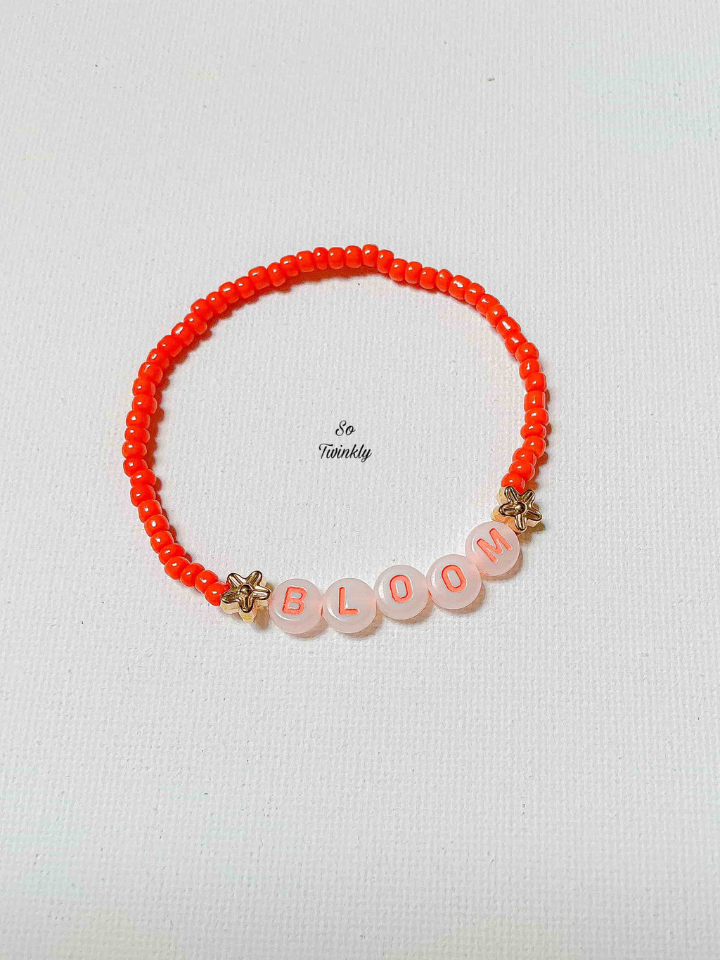 Flat lay of BLOOM bracelet featuring vibrant neon beads and a motivational charm in a fun, empowering design