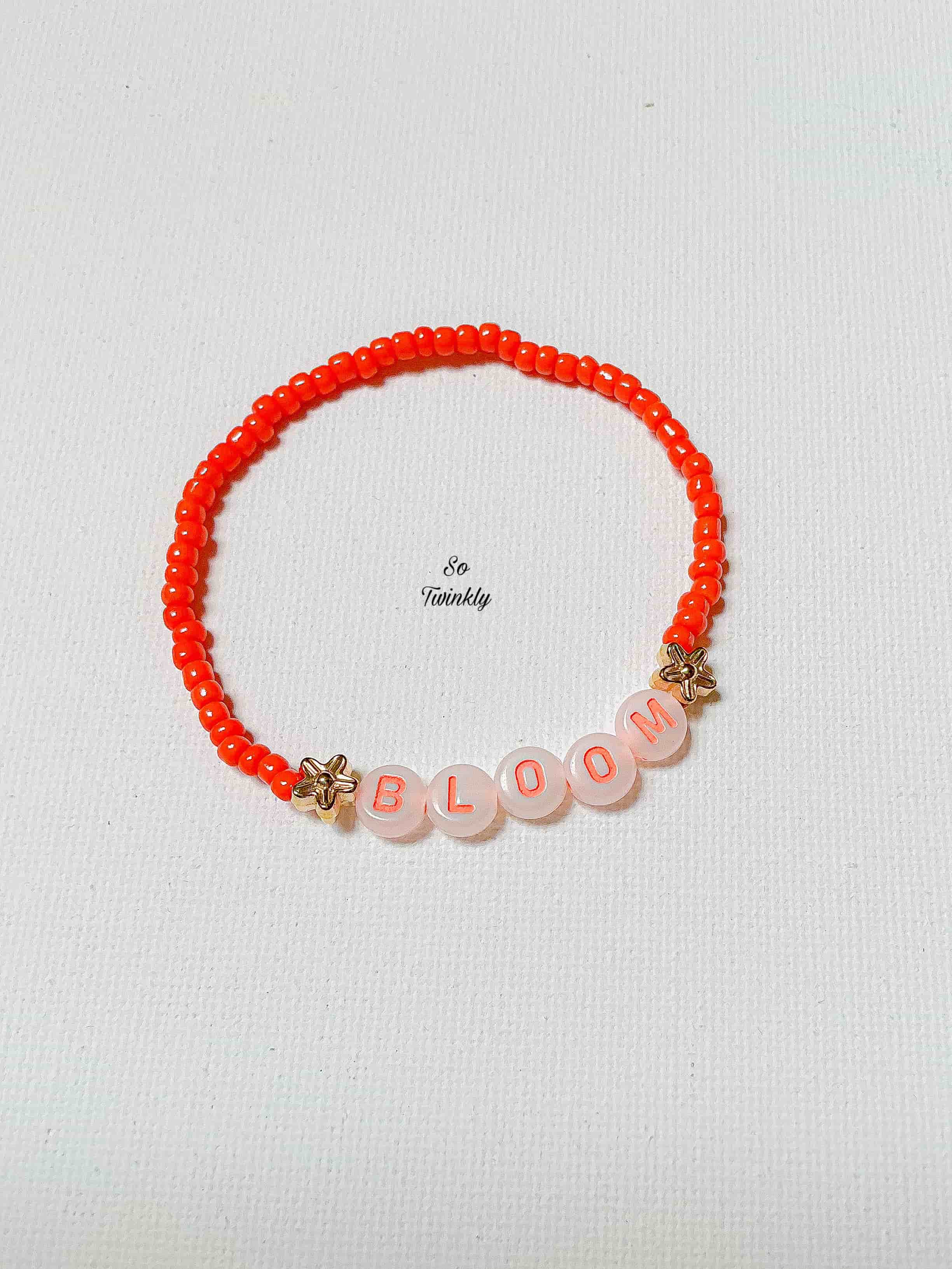 Flat lay of BLOOM bracelet featuring vibrant neon beads and a motivational charm in a fun, empowering design