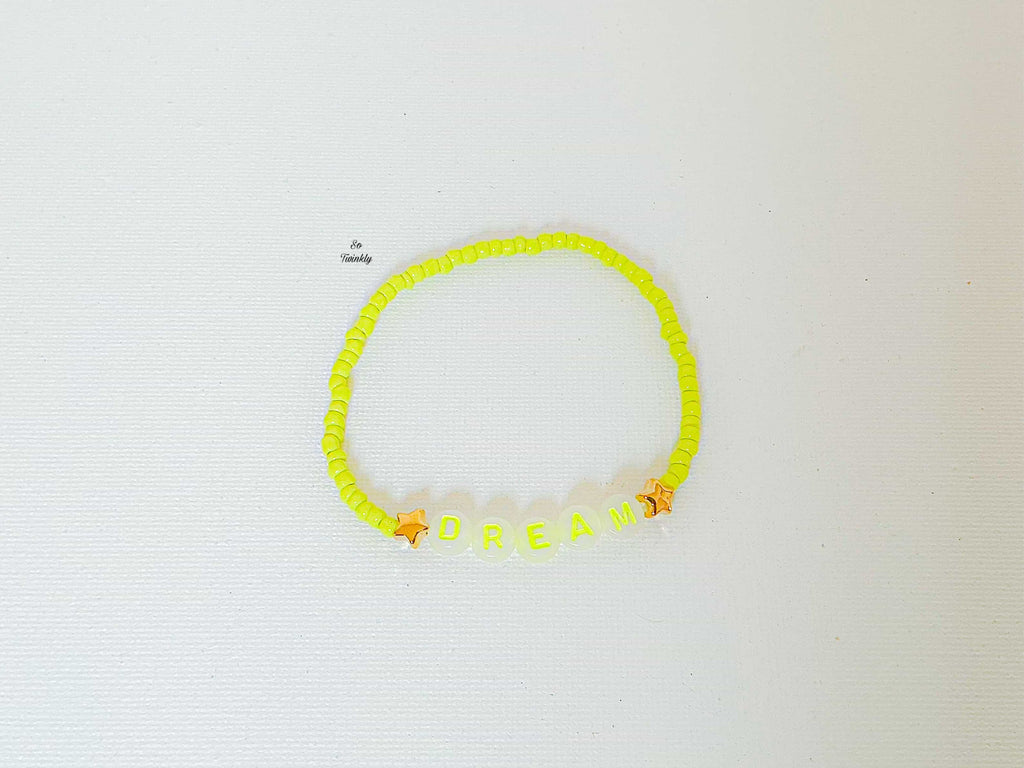 Flat lay of vibrant neon yellow Dream bracelet featuring acrylic pearls and bold message bead at the center