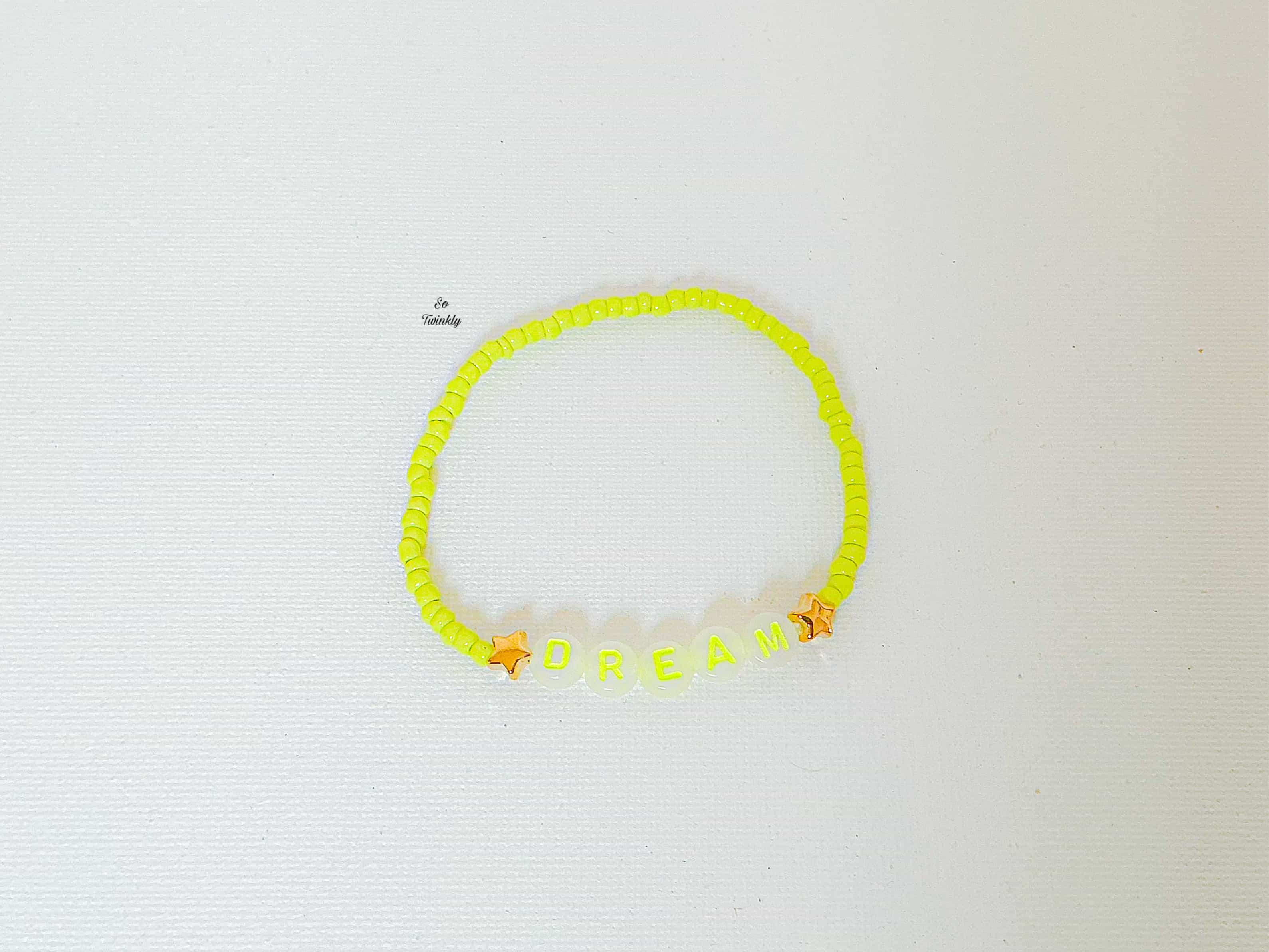 Flat lay of vibrant neon yellow Dream bracelet featuring acrylic pearls and bold message bead at the center