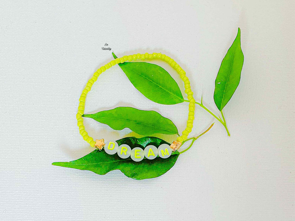 Handmade bracelet with neon yellow acrylic beads and a central message charm that says “Dream”