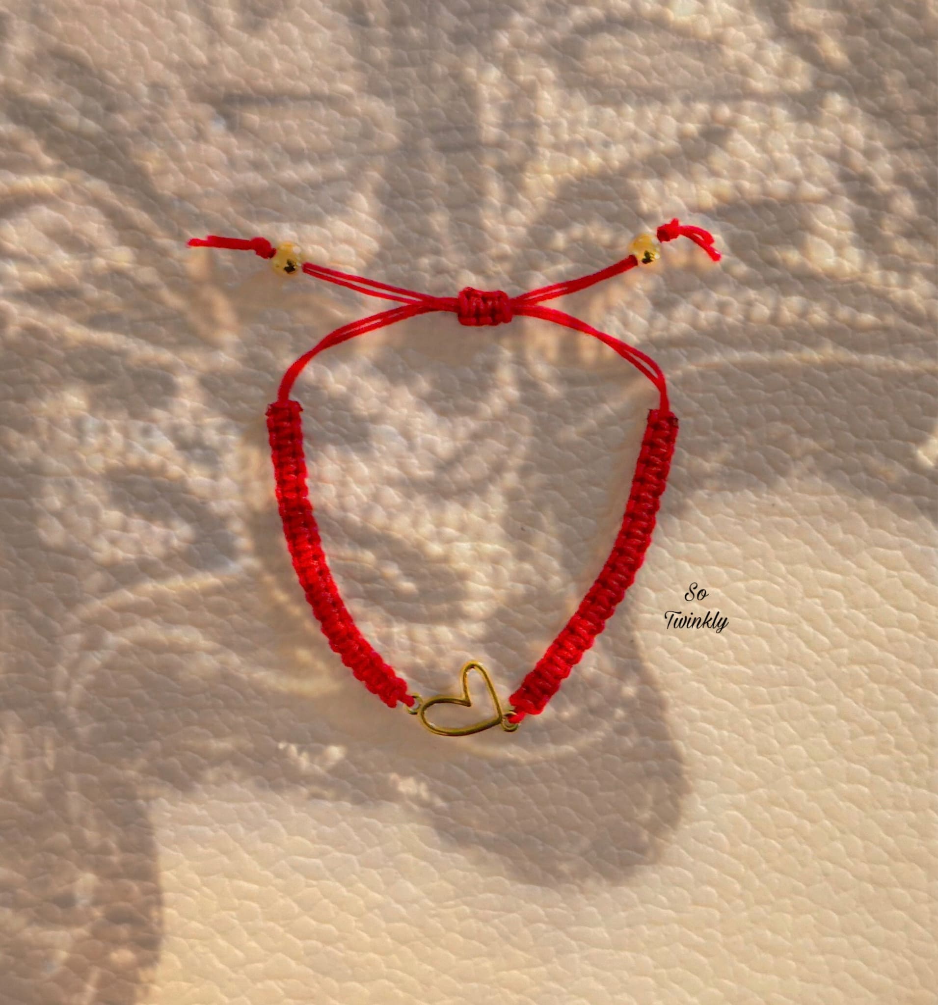 Flat lay of golden heart charm bracelet with adjustable nylon cord in a delicate, minimalist design