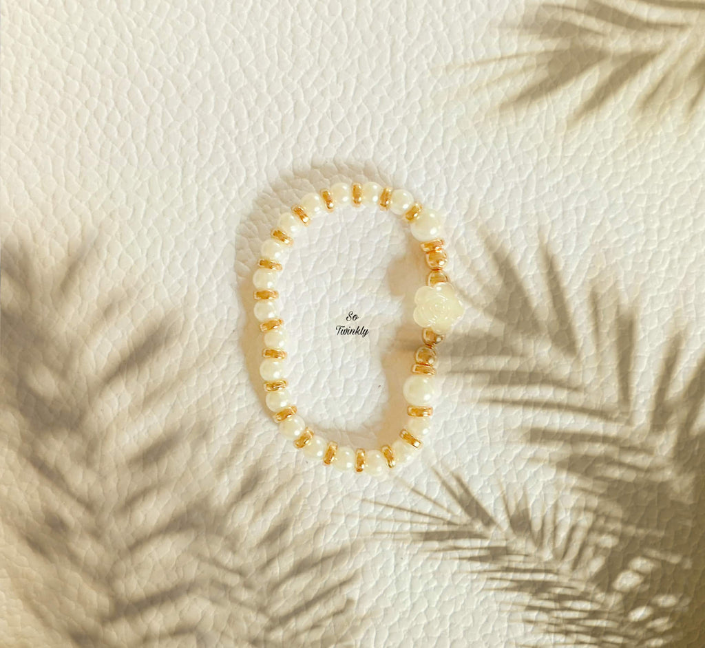 Flat lay of rose charm bracelet featuring white and gold beads in a soft, elegant handcrafted design