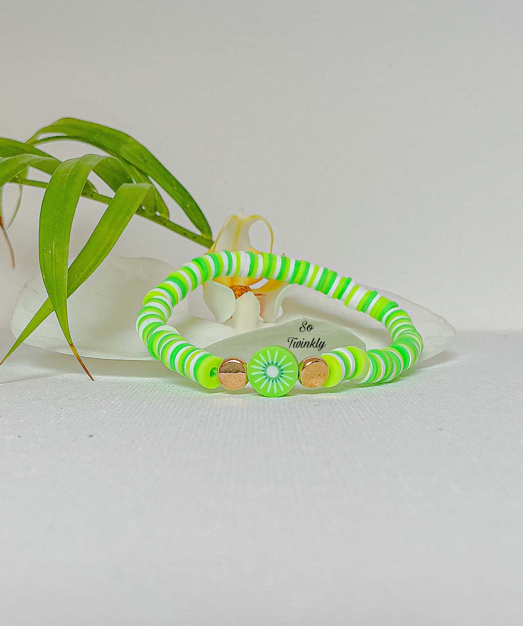 Handmade kiwi bracelet with neon green polymer clay beads and a playful kiwi slice charm