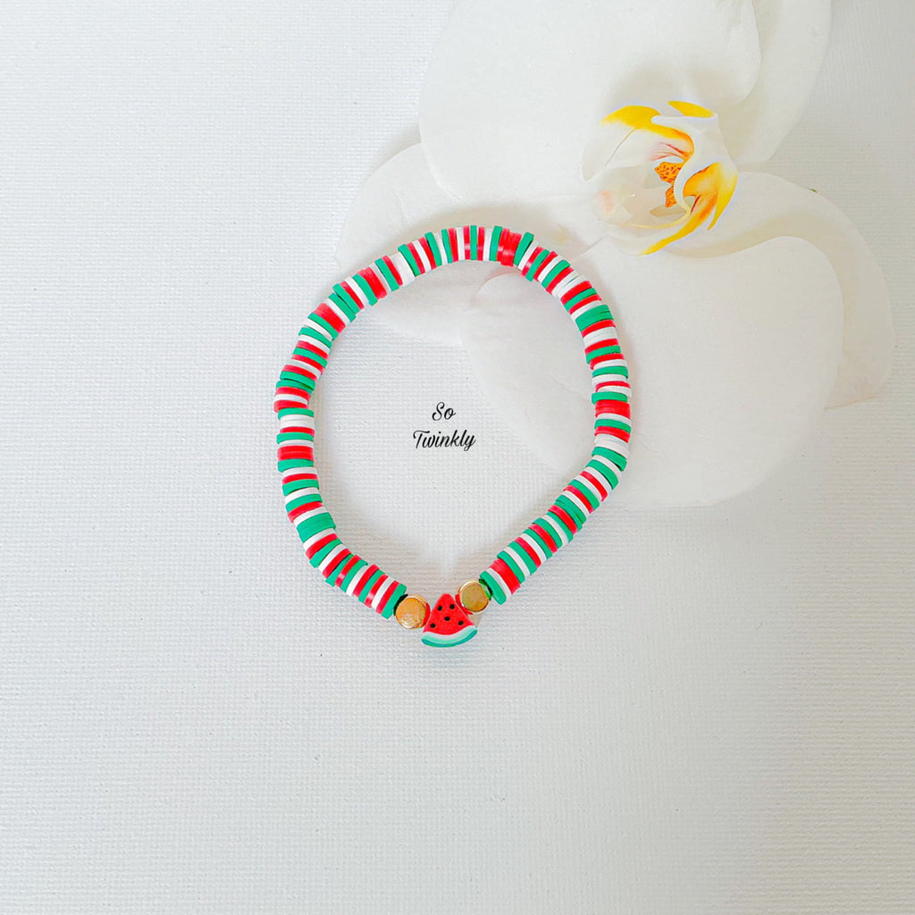 Flat lay of watermelon bracelet featuring gold pearls, colorful clay beads, and a watermelon charm