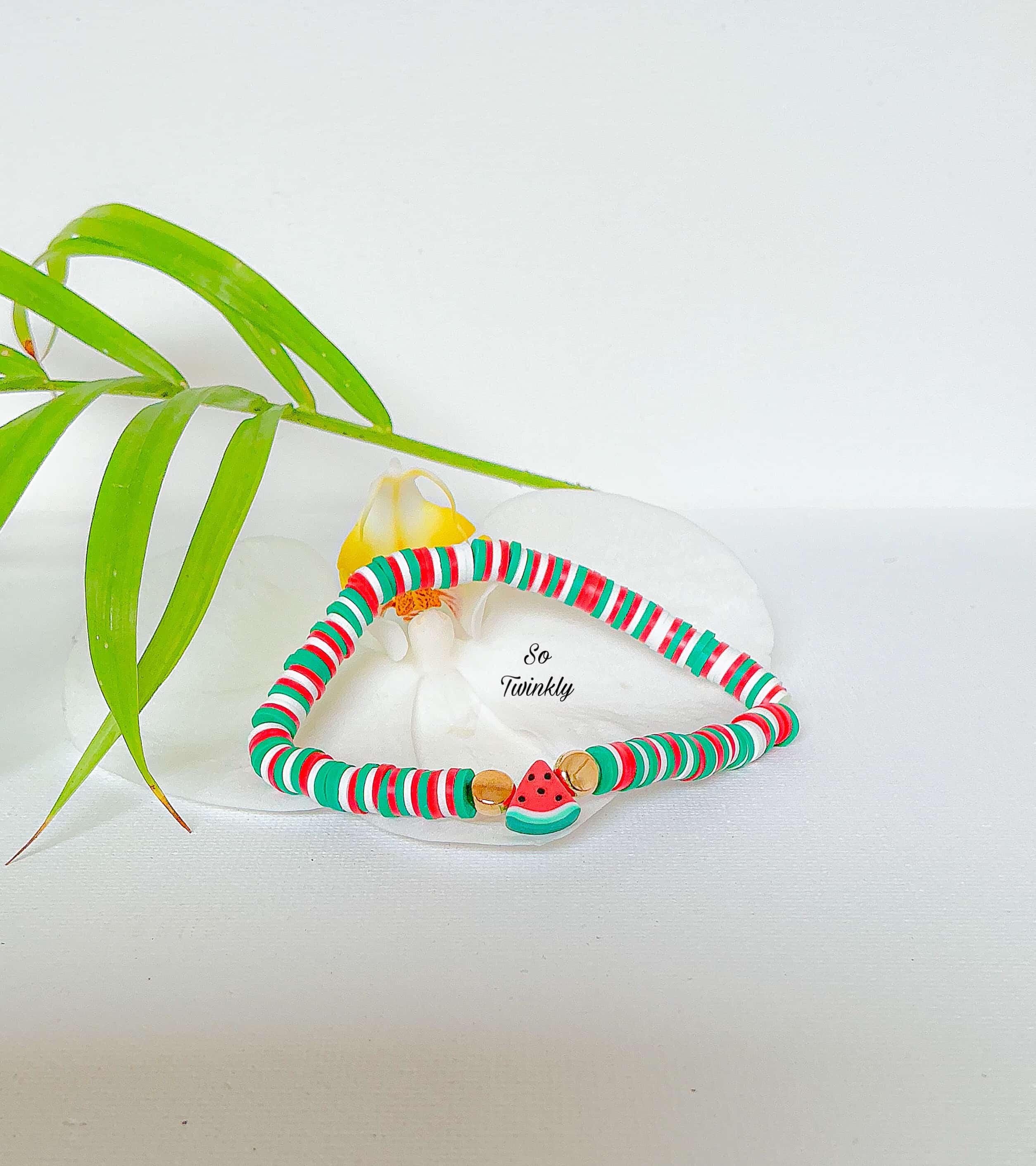 Handmade watermelon bracelet with red, green, and white polymer clay beads and a watermelon slice char