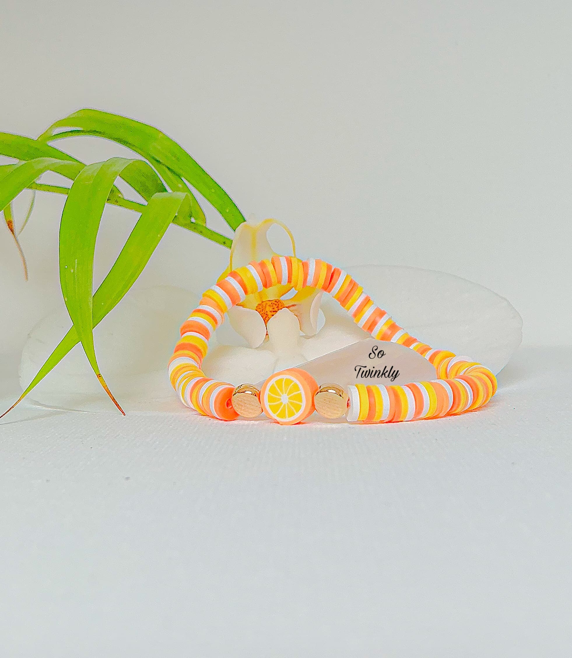 Handmade orange bracelet with warm orange and peach polymer clay beads and an orange slice charm