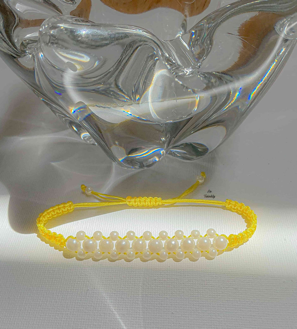 Flat lay of customizable macramé bracelet featuring white pearls and nylon cord in delicate, handcrafted design
