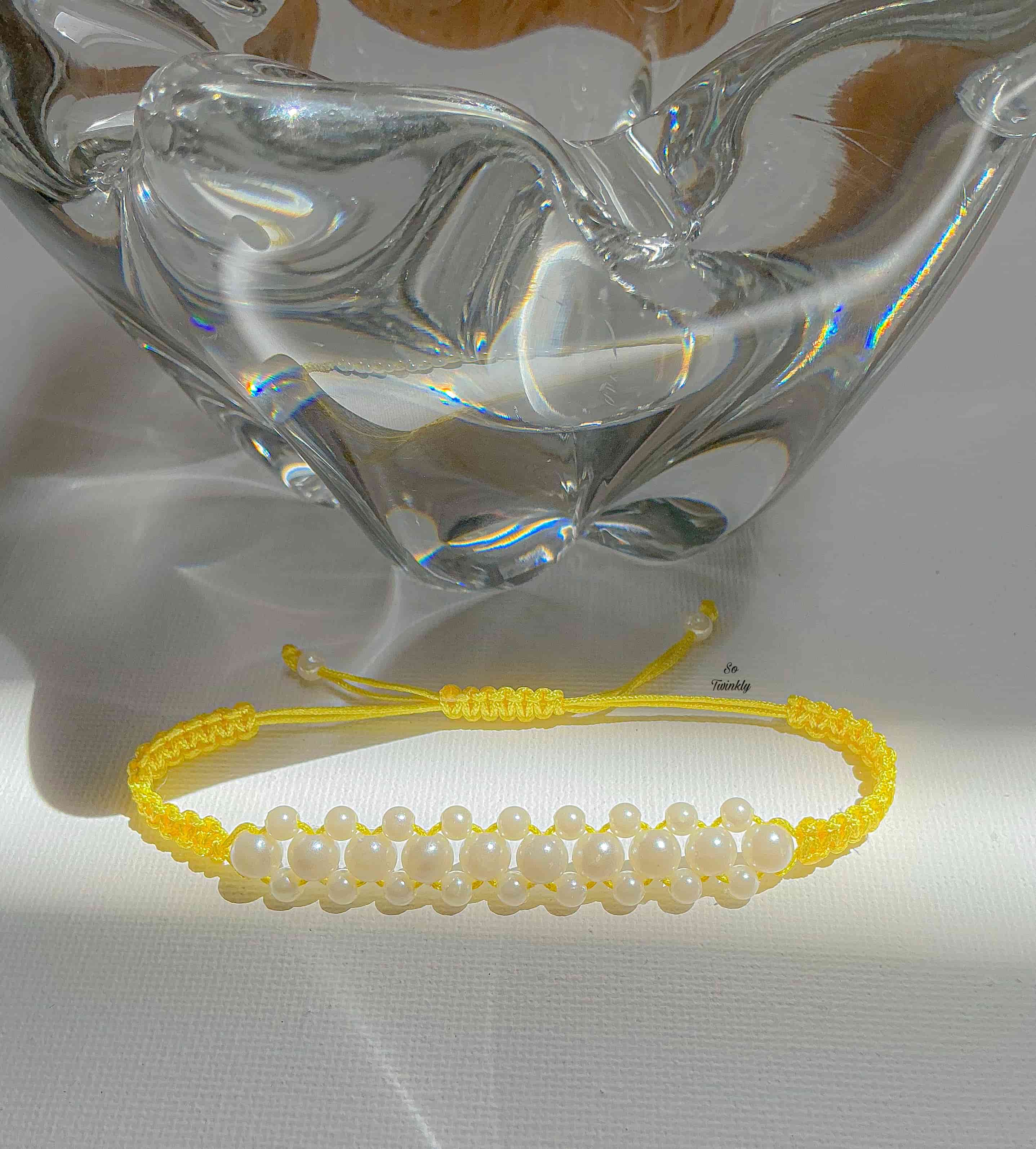 Flat lay of customizable macramé bracelet featuring white pearls and nylon cord in delicate, handcrafted design
